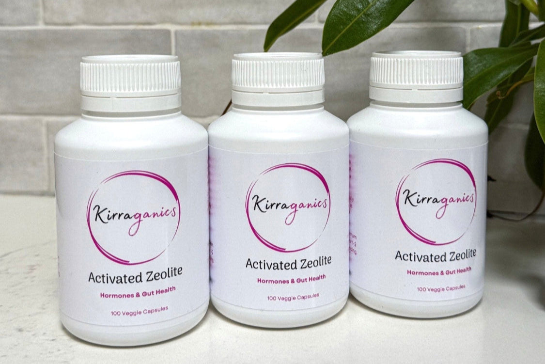Three bottles of Kirraganic Activated Zeolite on a bathroom counter with a plant in the background.