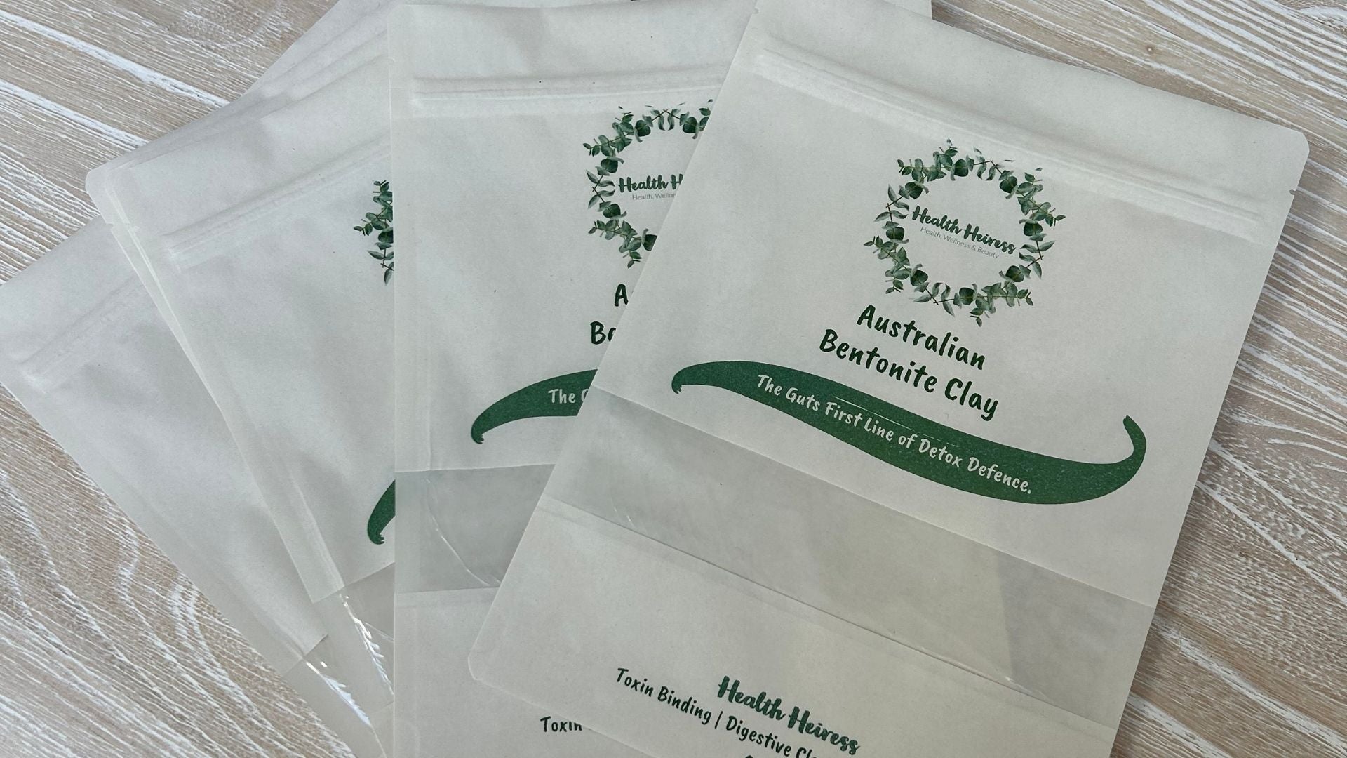 Clear plastic packages with green text and branding on a wooden surface