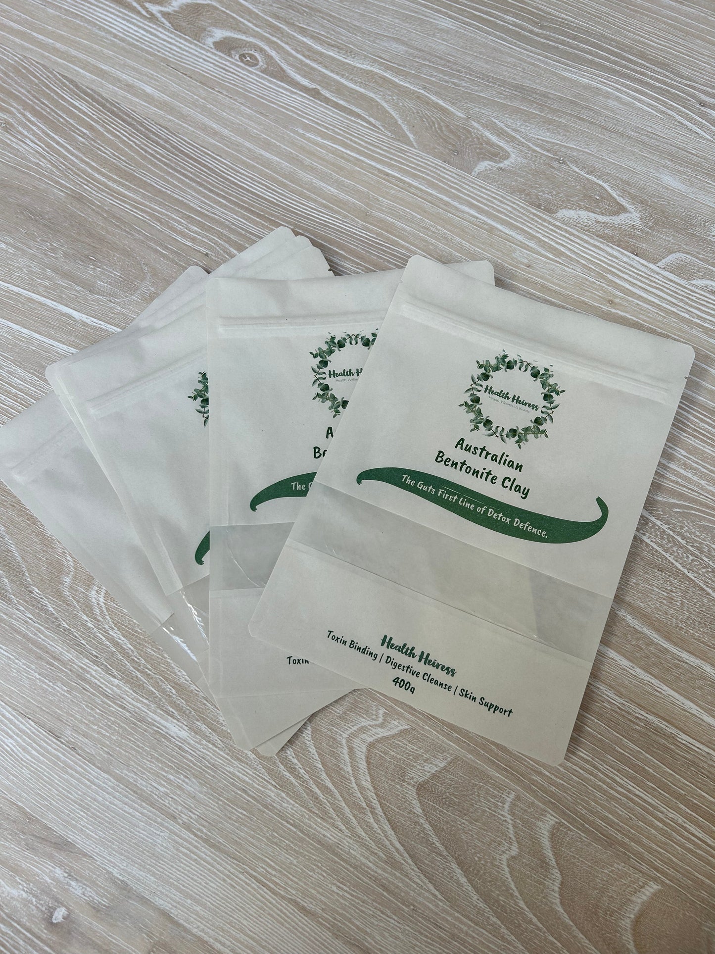 Health heiress product bags. White packets with green text and logo on a wooden surface